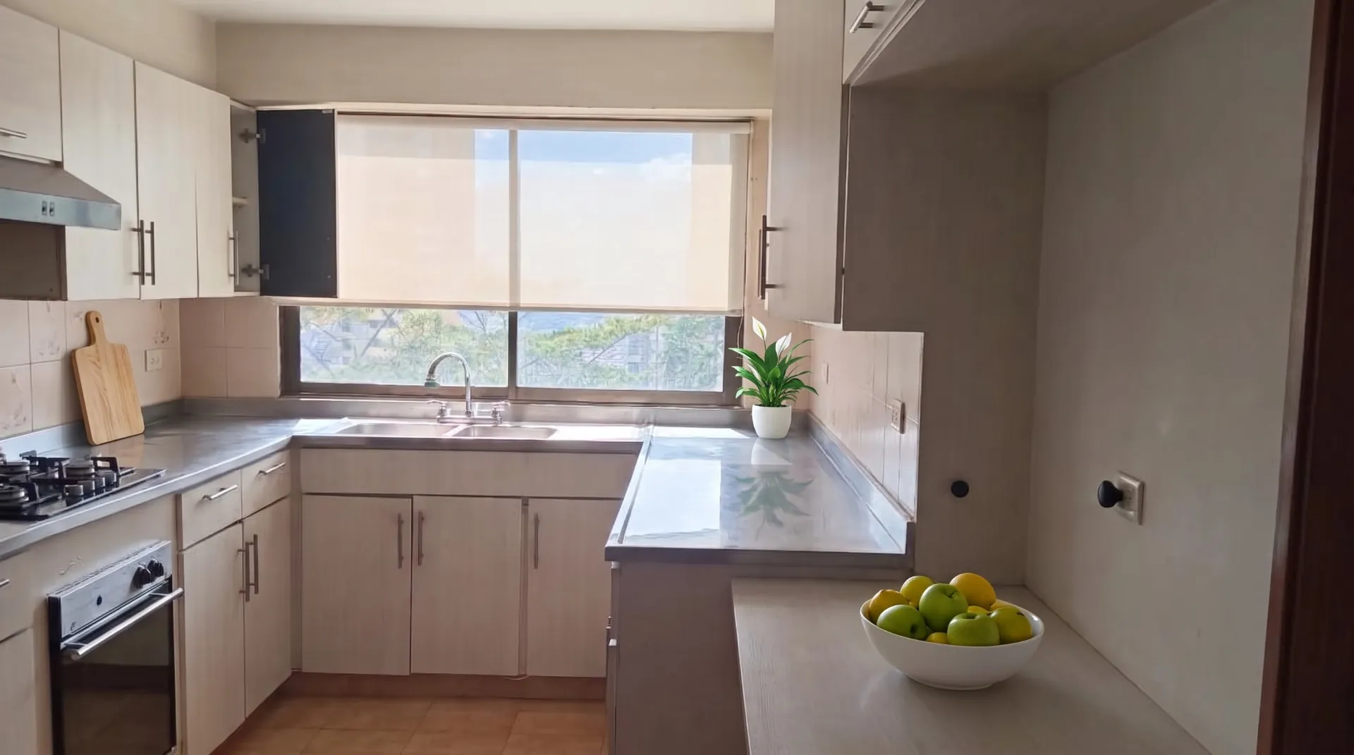 La misma cocina con una tabla de picar, una planta y un bowl de frutas agregados virtualmente.