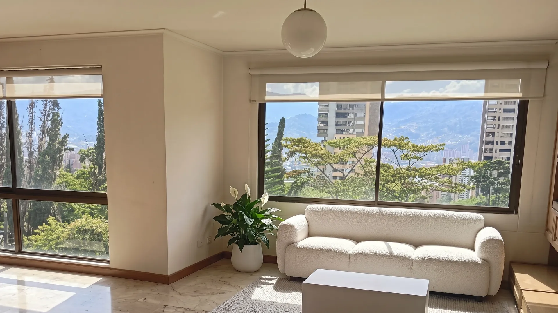 La misma sala con amoblamiento virtual: sofá blanco, mesa baja y una planta.